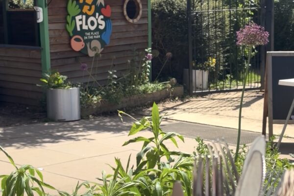 Flo's Hatch outdoor café kiosk at Flo's Place in the Park, Florence Park, with bunting, garden planting and a lunch table in the foreground.